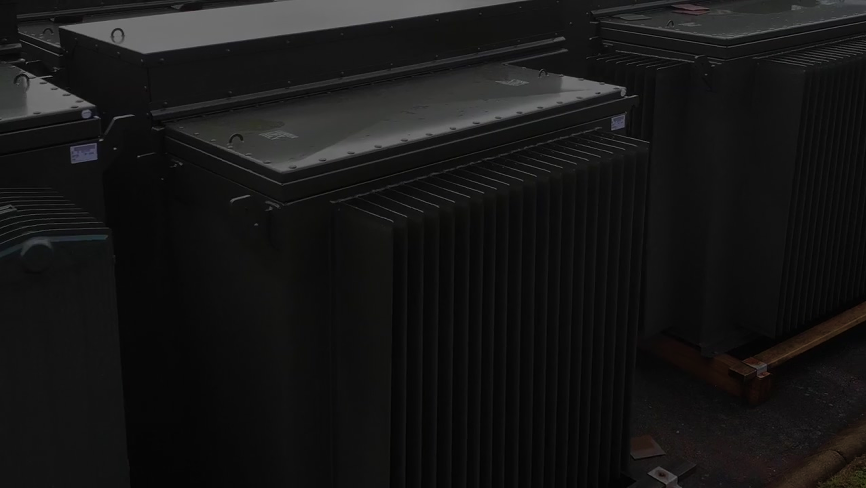 Large pad mounted transformer with cooling fins arranged outdoors on a concrete surface.