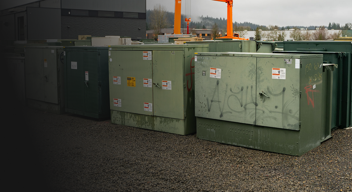 Rows of green used surplus transformers in a Maddox yard