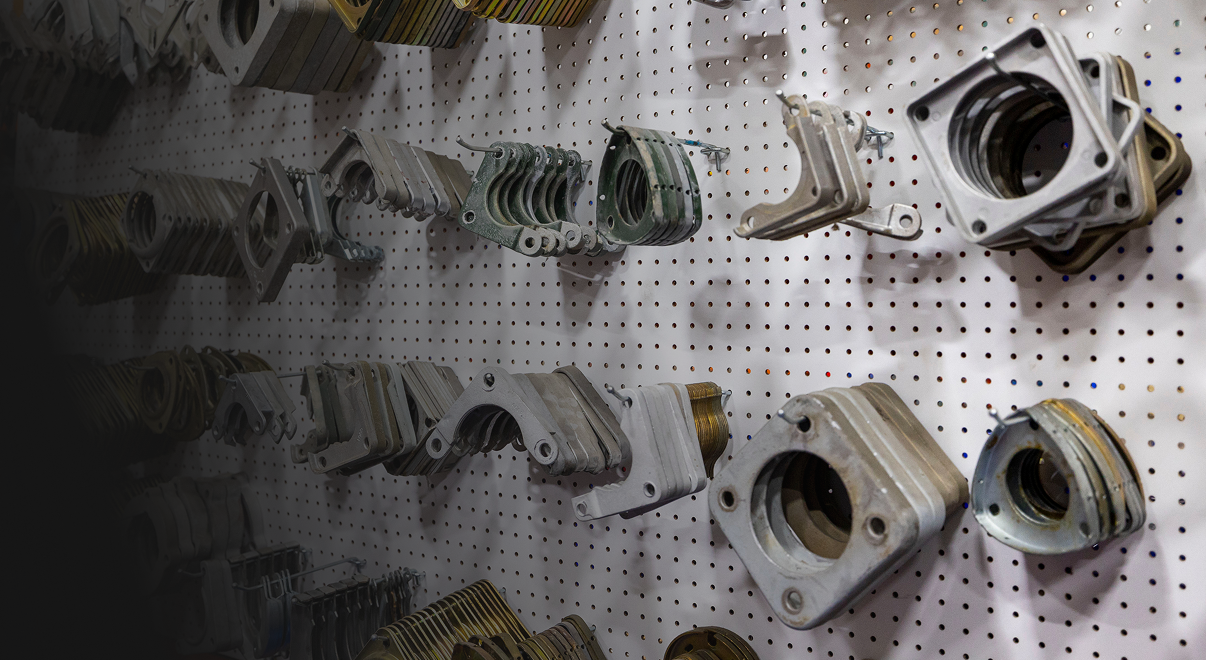 Various metal transformer parts organized and hanging on a perforated white pegboard wall.