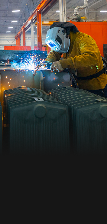 Worker in protective gear welding a Maddox transformer